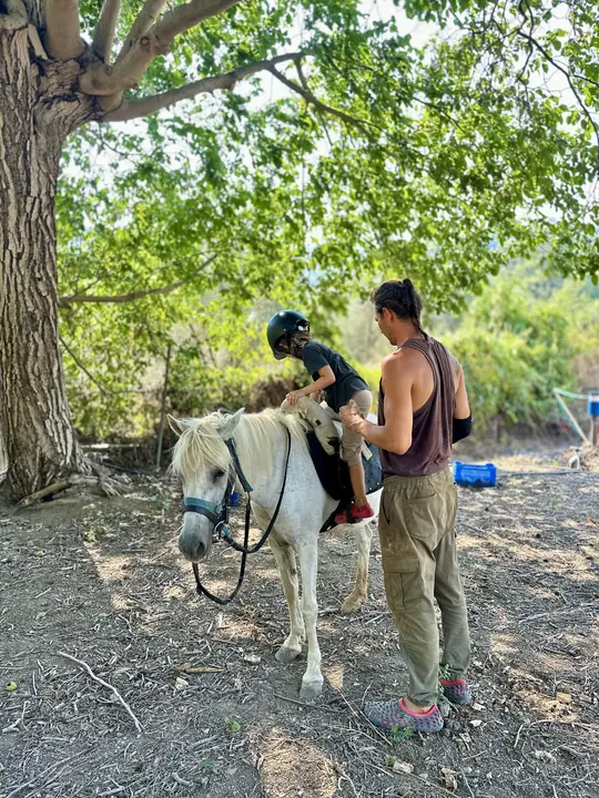 A child riding at the farm, guide beside them